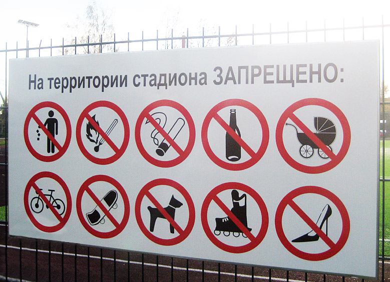 Информационный щит с запрещающими знаками на ограждении стадиона