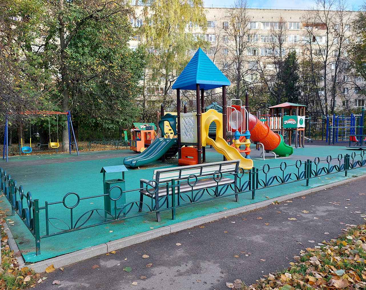 Большая детская площадка с травмобезопасным покрытием зеленого цвета в городском районе